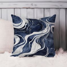 a blue and white pillow sitting on top of a fur covered bed next to a wooden headboard