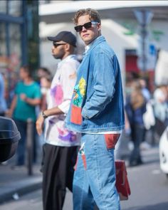 a man standing on the street with his hands in his pockets and looking at something