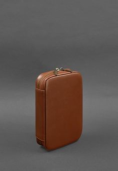 a brown piece of luggage sitting on top of a gray floor next to a wall