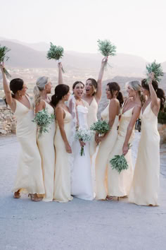 a group of bridesmaids holding up flowers and greenery in front of the camera