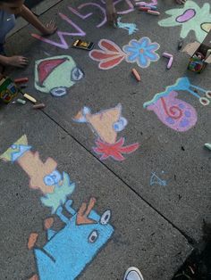 children are drawing on the sidewalk with chalk and crayon pencils in front of them