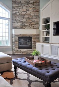 a living room filled with furniture and a fire place in front of a stone fireplace