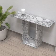 a marbled console table next to a potted plant