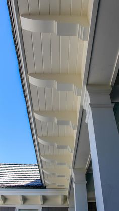 the underside of a white building with columns and roof tiles on it's sides