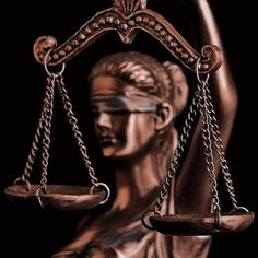 a statue of lady justice holding the scales of justice in front of a black background