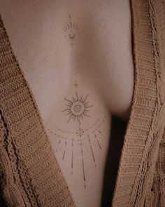 the back of a woman's breast with sun and moon tattoos on it