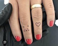 two people with matching tattoos on their fingers, one has a heart and the other has a cat's head