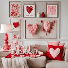 a living room filled with lots of pink and red decorations on the wall next to a white couch