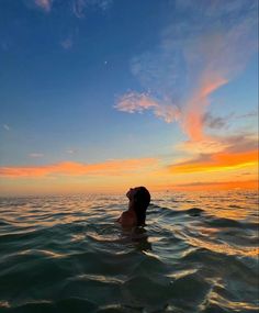 a man swimming in the ocean at sunset with his head above water's surface