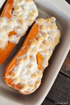 two pieces of bread with marshmallows on them in a white dish sitting on a wooden table