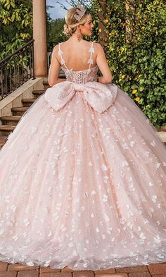 a woman in a pink ball gown standing on steps with her back to the camera