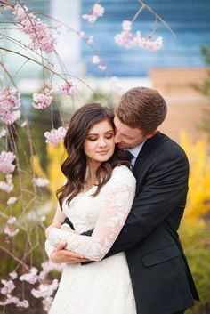 a bride and groom embracing in front of pink flowers