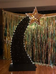 a large star on top of a wooden floor in front of tinsel and streamers