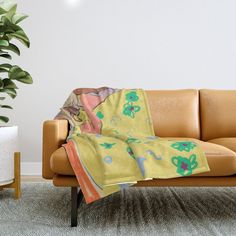 a couch with a blanket on it next to a potted plant