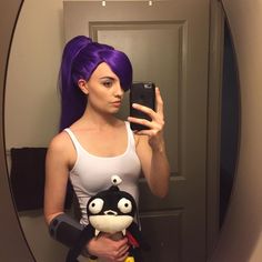 a woman with purple hair taking a selfie in front of a mirror holding a cell phone