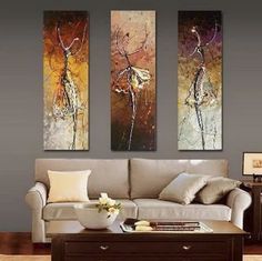 three paintings are hanging on the wall above a couch and coffee table in a living room