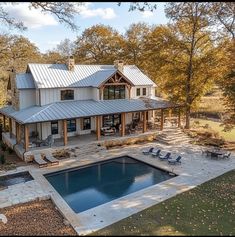 an aerial view of a house with a pool in the foreground and deck chairs around it