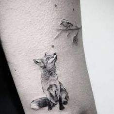 a small fox and bird tattoo on the arm