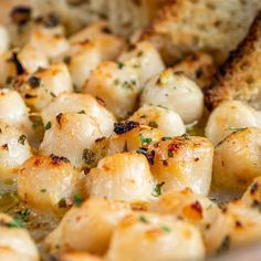 scallops and bread in a white bowl with herbs on top, ready to be eaten