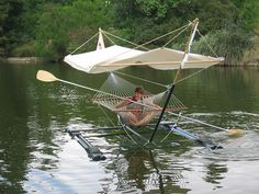 a man sitting in a hammock on the water with a sail boat attached to it