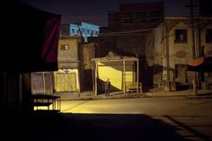 an empty street at night with buildings in the background and a person standing on one side