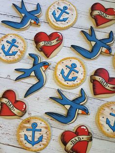 decorated cookies are arranged in the shape of birds and anchors on a white wooden surface