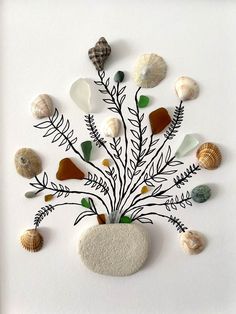 an arrangement of seashells and sea glass arranged in a vase on a white surface