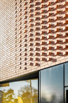 the side of a brick building that has windows on both sides, and a yellow bench in front of it