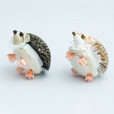 two figurines of hedgehogs with bows on their heads, one in the shape of a bird