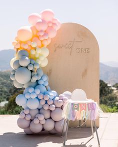 an arch made out of balloons and streamers for a baby's first birthday