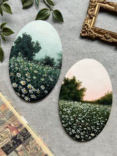 two oval paintings sitting on top of a table