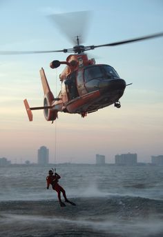 a man is being pulled into the water by a helicopter