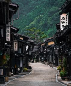 an empty street with mountains in the backgrouds and trees on both sides