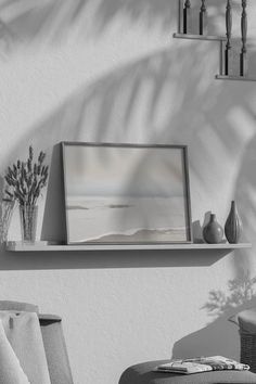 a black and white photo of a shelf with vases on it next to a chair