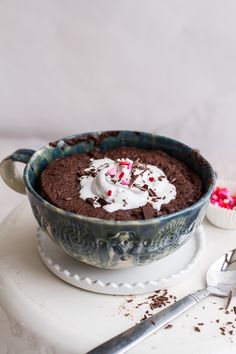 a bowl of chocolate pudding with whipped cream and sprinkles on the side