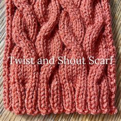 a red knitted scarf sitting on top of a wooden table