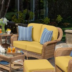 an outdoor patio furniture set with yellow cushions and blue throw pillows on the couches