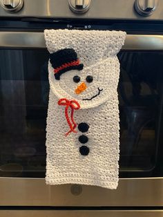 a knitted snowman towel hanging on an oven door