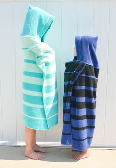 two young boys standing next to each other wrapped in blue and green striped toweles