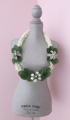 a mannequin with white flowers and green leaves on it's neckline