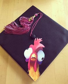 a graduation cap with a rooster on it and tassels hanging from the side