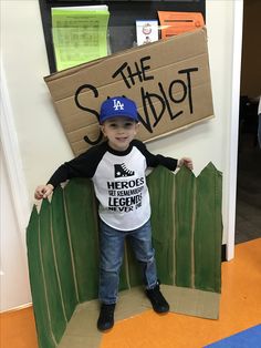 a young boy standing in front of a cardboard sign