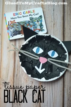 a paper plate with a black cat on it next to a book and some scissors