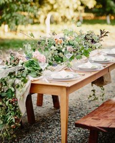 a wooden table topped with plates and flowers