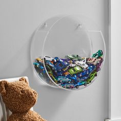 a teddy bear sitting in front of a wall mounted glass plate with cars on it