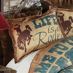 a bed topped with lots of pillows covered in cowboy themed sheets and pillow shampoos