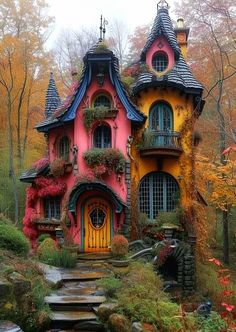 a pink and yellow house with lots of plants on the roof is surrounded by trees