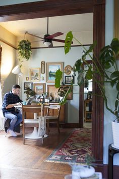 a man sitting at a table in front of a plant