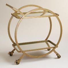 two tiered gold metal serving cart with glass shelves and wheels, on white background