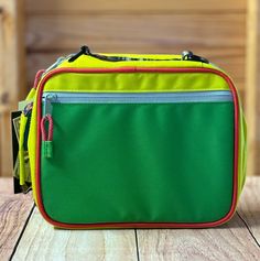 a green and yellow bag sitting on top of a wooden table